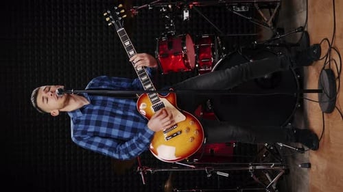 Musicien jouant à la guitare électrique et chantant une chanson dans un studio d'enregistrement sonore