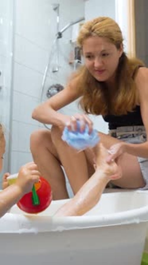 Mother Washing Daughter's Leg in Bath Tub