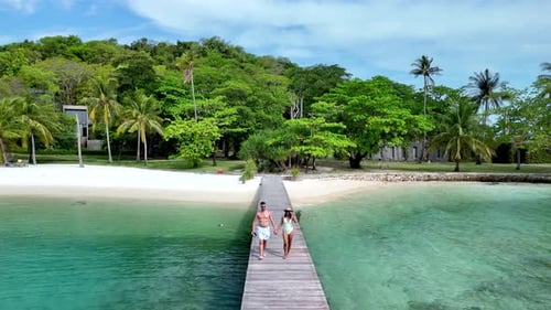 Couple Walking Hand in Hand Along a Serene Wooden Pier on Koh Mak Koh Kham Island in Thailand