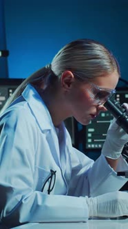 Female Scientist Analyzing Sample Under Microscope in Lab