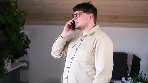 Man Talking on Phone Indoors with Computer
