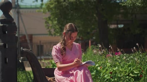 Woman Sits on Bench and Draws in Park