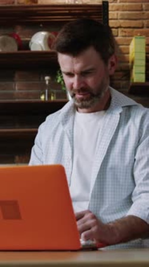 Man Smiling While Typing on Laptop at Home