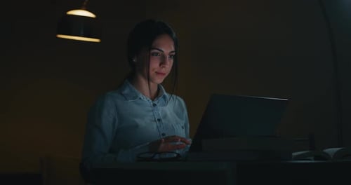 Slow motion of a young beautiful business woman is working with a computer in the evening in a off