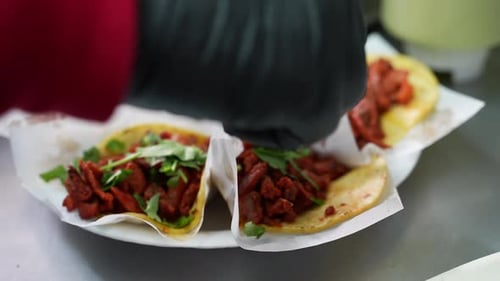 Sprinkling chopped cilantro on a platter of street tacos - food truck series