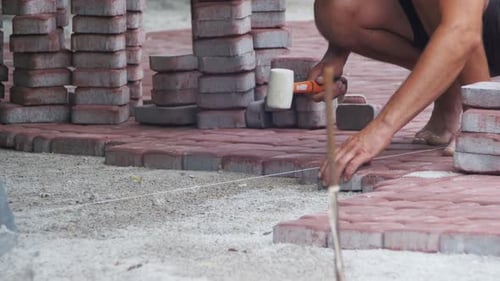 Person Laying Red Brick Pavers Outside