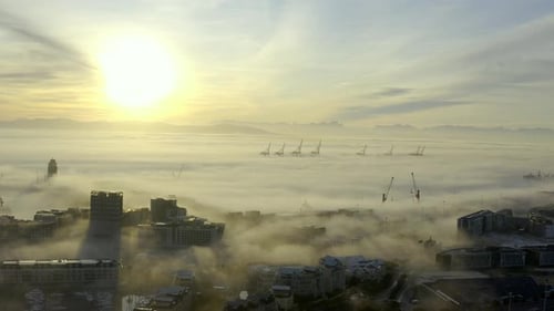 City Buildings Emerging from Fog at Sunrise