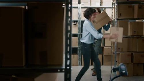Male and Female Warehouse Workers Have Fun Dancing. Happy People in Storeroom full of Shelves with