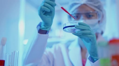 Scientist Drops Liquid Into Petri Dish in Lab