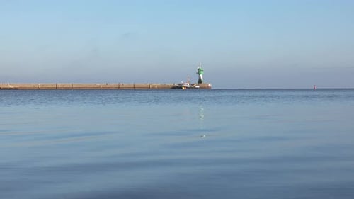 Peaceful seaside view in Luebeck-Travemuende with a long pier, green lighthouse, and calm blue