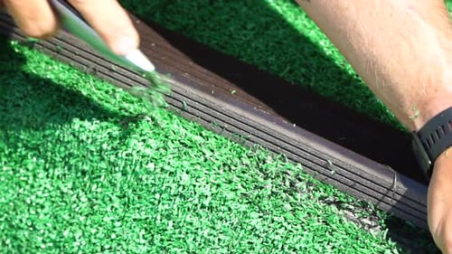 Man Cuting Artificial Grass Carpet with Knife Artificial Turf Close Up on Hands