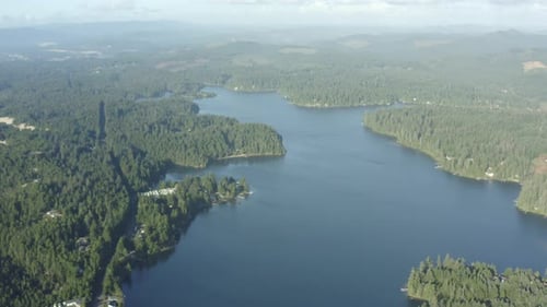 Aerial of lush forest surrounding a deep blue lake