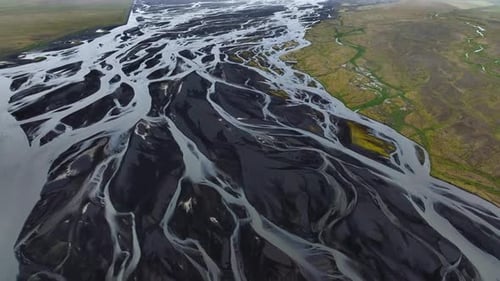 High angle panning shot showing a braided river flowing across a volcanic landscape, Iceland