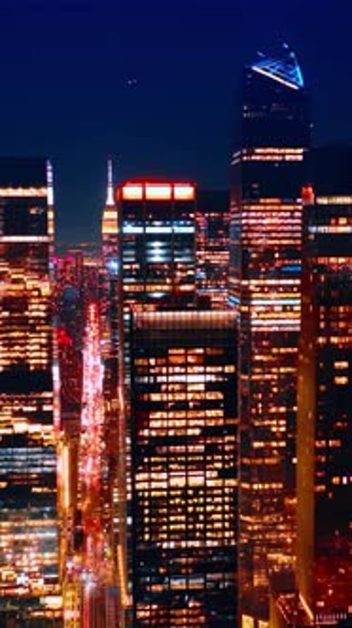 Spectacular skyscrapers with light in windows at the backdrop of dark blue sky.
