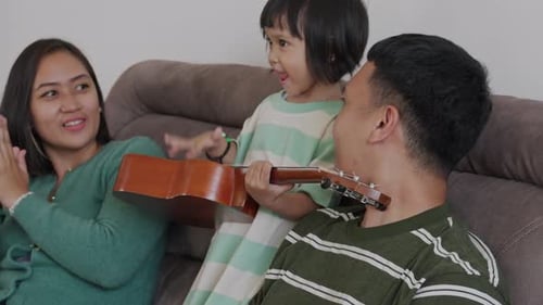 Family Relaxes Together on the Couch With Ukulele