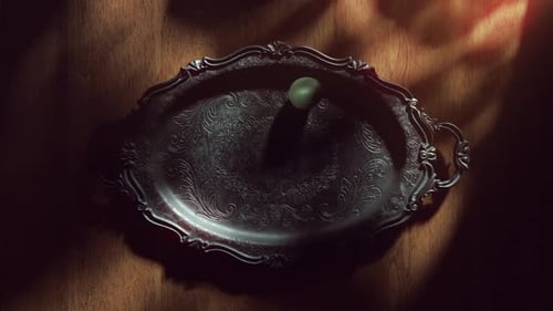 Green Easter egg rolling on a vintage dark metal tray.