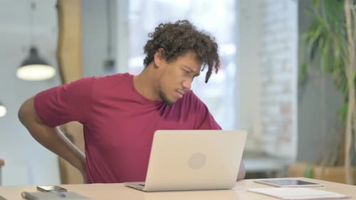 Man Working at Computer Stretches His Back