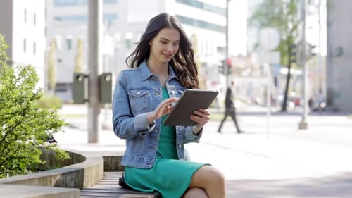 Smiling young woman enjoys tablet technology on a sunny city street