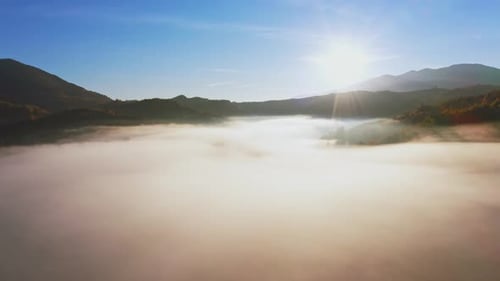 Sunrise Light Among Clouds Above Mountainous Canyon in Mist