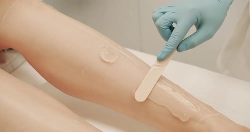 Wax Application on Woman's Leg Using Spatula