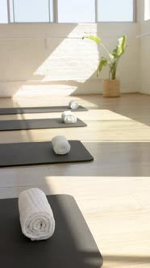 Vidéo verticale : tapis de yoga avec serviettes roulées dans un studio de Pilates lumineux, prêts pour les cours, espace de copie