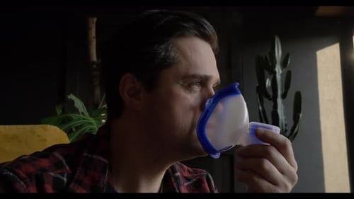 middle-aged white man with a cold inhales medicine through a nebulizer at home