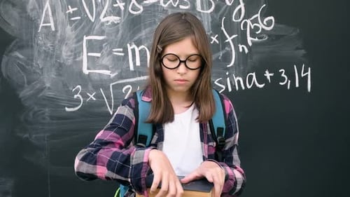 Student Reading Book in Front of Chalkboard