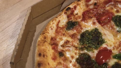 close up shot of delicious Italian pizzas delivered in boxes on the wooden table at home, sliding