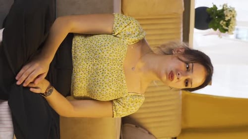 Expressive Woman Sitting Cross-Legged on Couch Indoors