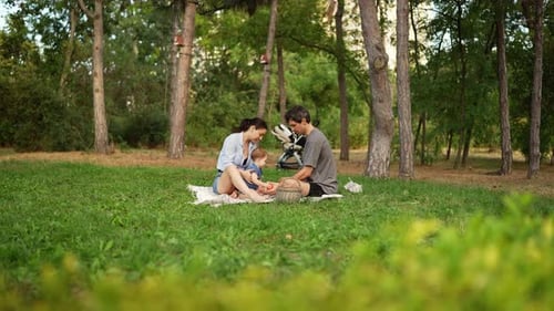 Side View of a Brunette Man in a Gray Tshirt with His Wife and Little Girl Talking and Spending Time