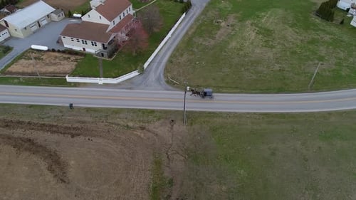 Amish Horse and Buggy Riding along Countryside Road Passing Amish Homes on a Winter Day as seen by a