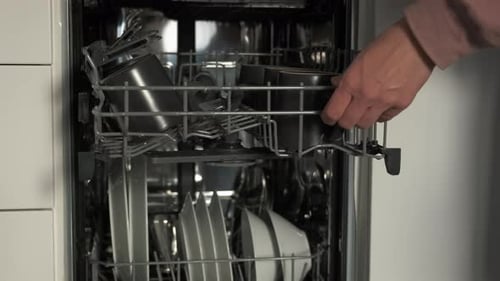 Loading Dishes into a Modern Stainless Steel Dishwasher