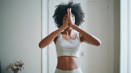 Woman meditates indoors with hands in prayer position