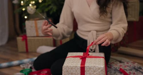 Woman Wraps Christmas Gift by Tree