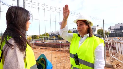 Female architect and engineer discussing project at construction site