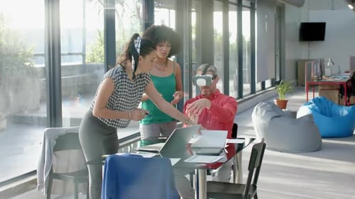 Caucasian businessman wearing vr headset while colleagues watching him at office