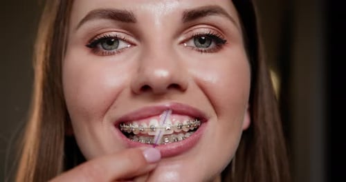 Smiling Woman Cleans Her Braces with Small Brush