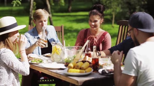 Friends Gather for Relaxing Meal Outdoors on Sunny Day