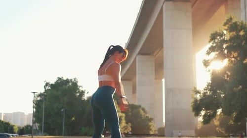 Sporty Woman Doing Backward Squats at City Park During Sunny Day