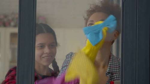 Woman and Child Cleaning Glass Together at Home