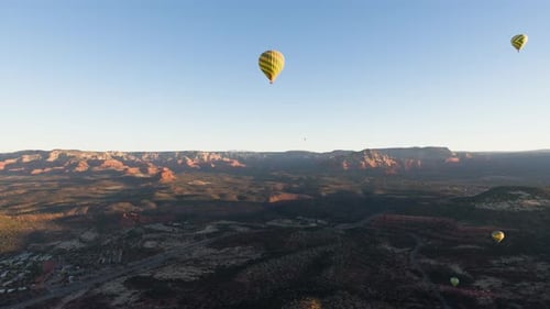 Hot air balloon ride POV, multiple yellow balloons in air; Sedona, Arizona