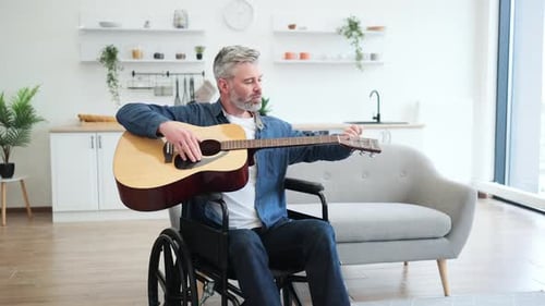 Man in Wheelchair Plays Acoustic Guitar and Smiles