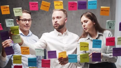 Team of Business People is Doing Brainstorm at a Meeting Using Stickers on the Glass Office Workers