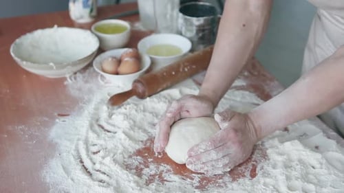 Experienced professional cook, baker forms dough and starts to cook bread using traditional methods.