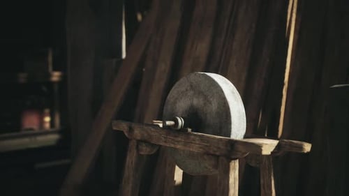 A Vintage Sharpening Stone on a Wooden Stand in a Rustic Workshop