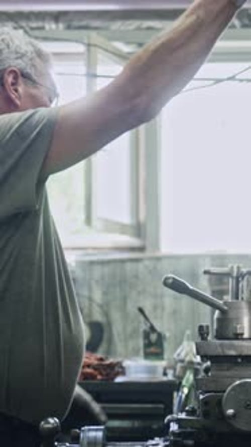 Almaty, Kazakhstan - June 27 2024: Experienced machinist using lathe machine in industrial setting