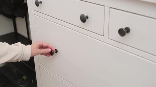 Hand opening drawer in wardrobe closet. Close-up indoor shot in household setting. Home storage and