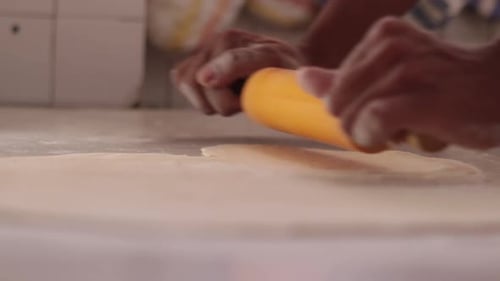 Hands Roll Dough with Rolling Pin in Kitchen