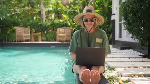 Woman Sitting in Near the Swimming Pool Using Laptop
