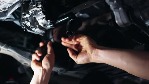 Mechanic Working on the Undercarriage of a Car in a Garage